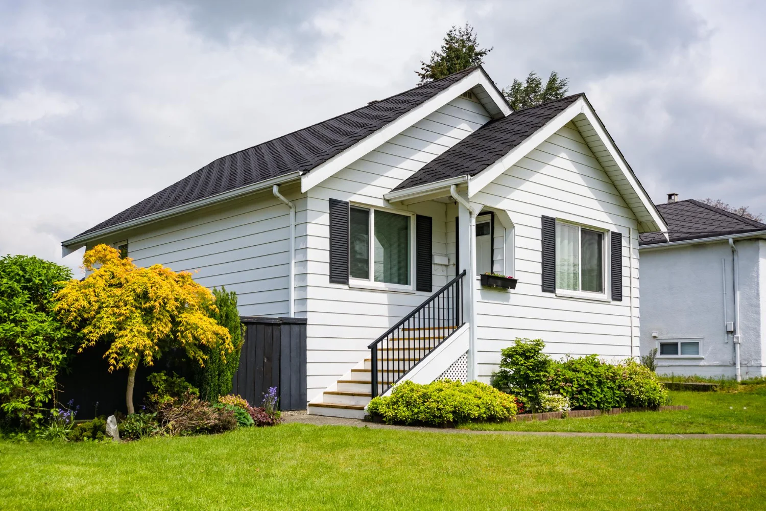 A charming small white house featuring a contrasting black roof, set against a clear blue sky
