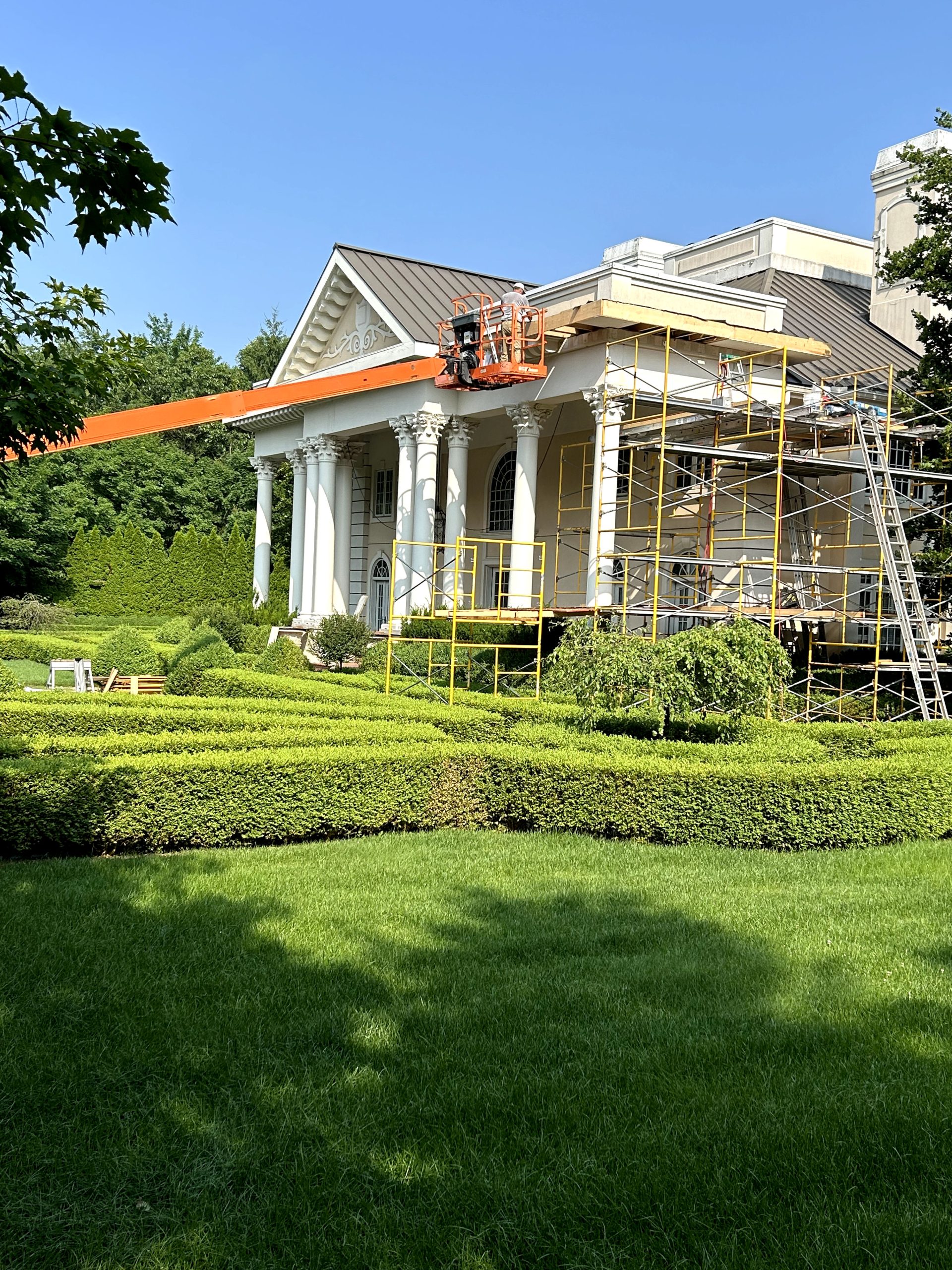 A large house with a crane on top, while workers are busy on the ground below, showcasing construction activity